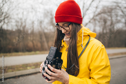 Woman photographer in yellow raincoat with vintage medium format camera