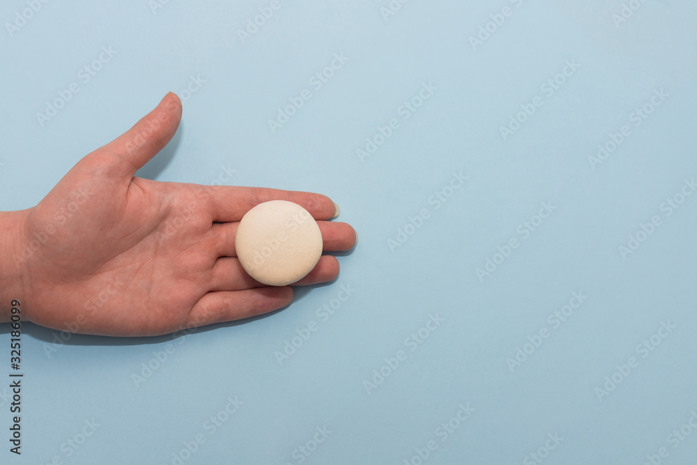 Macaroon cookie on female palm on blue flat background Macaroon cookie on female palm on blue flat background