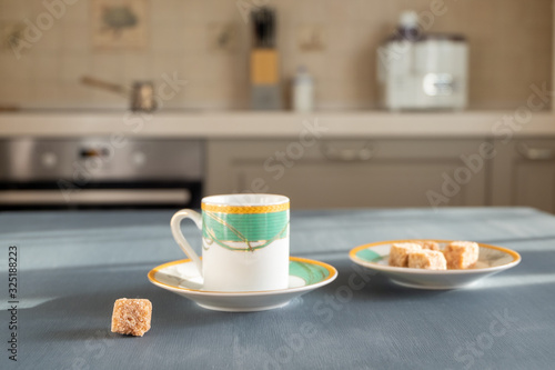 A beautiful coffee cup stands on a dark gray surface on a blurry background of the kitchen interior