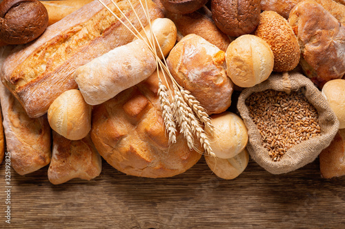 Foto Fresh baked bread and wheat ears, top view