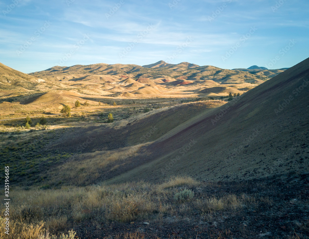 Incredible gold and red hills of clay fossil beds in a semi desert mountain valley on a sunny day of the painted cove trail at the john day fossil beds in Oregon