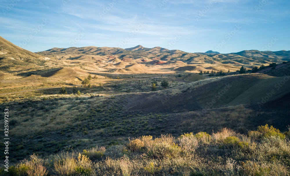 Incredible gold and red hills of clay fossil beds in a semi desert mountain valley on a sunny day of the painted cove trail at the john day fossil beds in Oregon