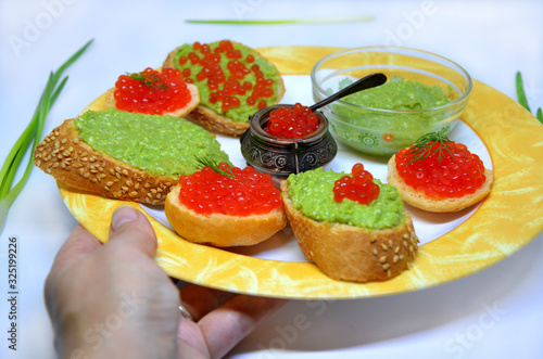  plate with sandwiches in hand with caviar and guacamole