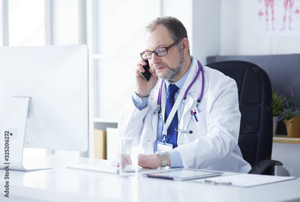 Portrait of senior doctor in office sitting at the desk Portrait of senior doctor in office sitting at the desk