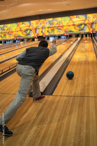 Adult man playing bowling in club. Male spending time enjoying weekend and playing in sport game.