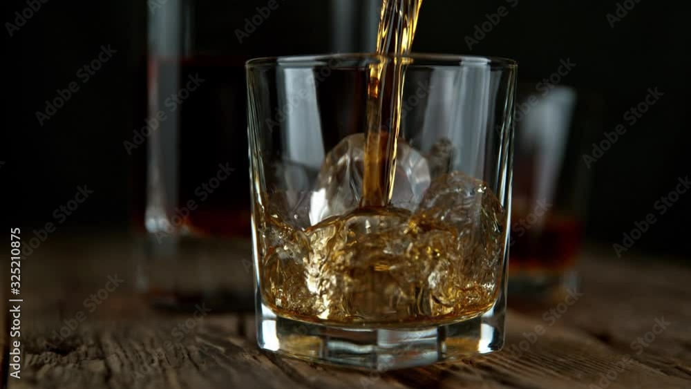 Super Slow Motion Shot of Pouring Whiskey into Glass with Ice Cubes at 1000fps with Camera Movement. Super Slow Motion Shot of Pouring Whiskey into Glass with Ice Cubes at 1000fps with Camera Movement.