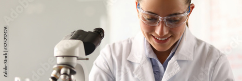 Fotografie Portrait of smiling young lab assistant writing down results of investigation