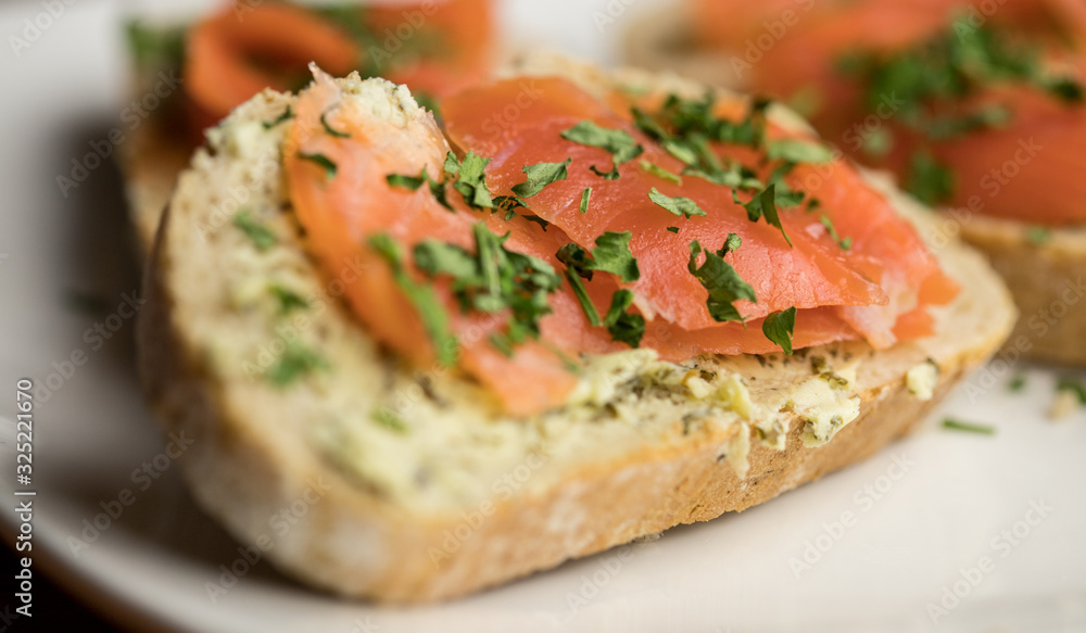 Close-up trout sandwiches with rainbow herb butter and fresh parsley served on a white plate