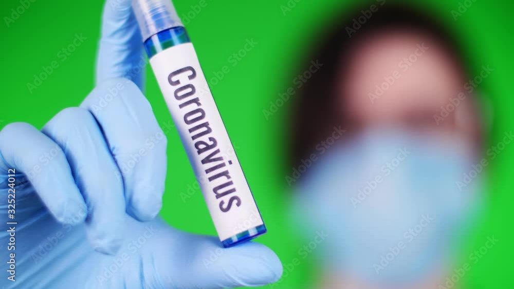 on a green background. close-up, doctor's hand in blue medical glove holds a test tube with the inscription coronavirus. The concept of medication for coronavirus. on a green background. close-up, doctor's hand in blue medical glove holds a test tube with the inscription coronavirus. The concept of medication for coronavirus.