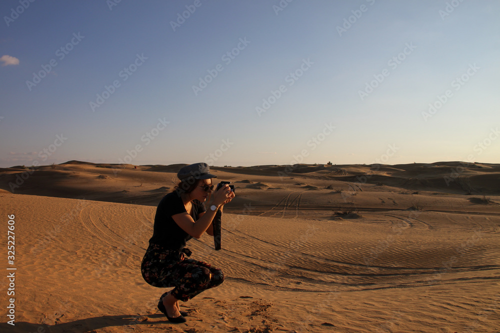 Crouched woman taking photos in the dunes of the Sahara desert