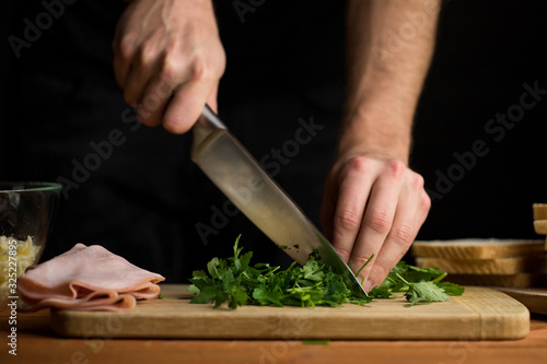 Person chopping fresh parsley visible chef hands and knife