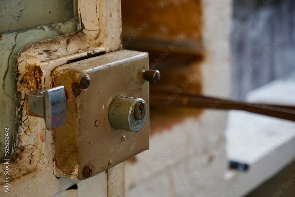 View of a rusted door lock on a very old white metal door View of a rusted door lock on a very old white metal door