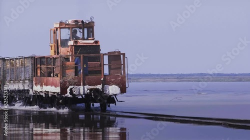 Old train rides on the railway laid in the water through the salt lake. train travels from water. Mined salt in Lake Burlin. Altai. Bursol. Russia. August 2019 