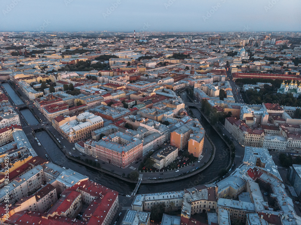 Aerial view of red and grey rooftops of Saint Petersburg. On the background Trinity Cathedra. View from above on Moyka river. Evening light. Drone photo concept. Orthodox church.