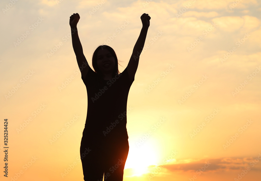Fototapeta premium woman silhouette arms up to the sunset feeling happy and freedom.
