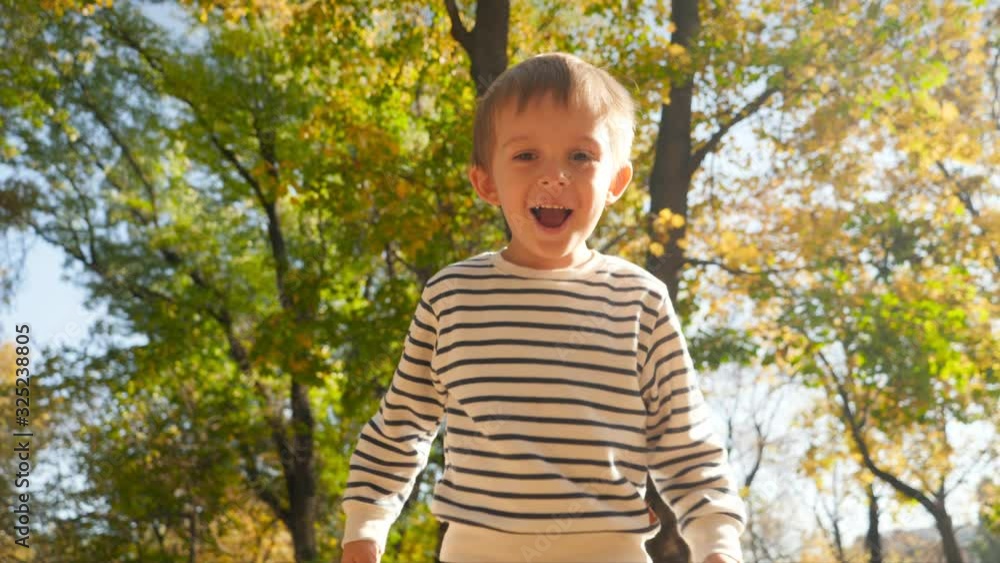 4k video of happy smiling little boy throwing autumn leave in camera and jumping high