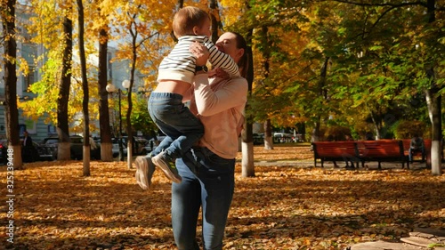 4k video of happy laughing young mother cathing her little son after jump and spinning him in autumn park photo