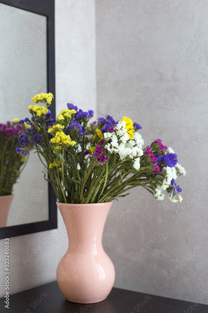 A multi-colored bouquet of dried flowers stand in a pink vase. A bouquet of flowers is reflected in the mirror. Flowers in a pink vase A multi-colored bouquet of dried flowers stand in a pink vase. A bouquet of flowers is reflected in the mirror. Flowers in a pink vase
