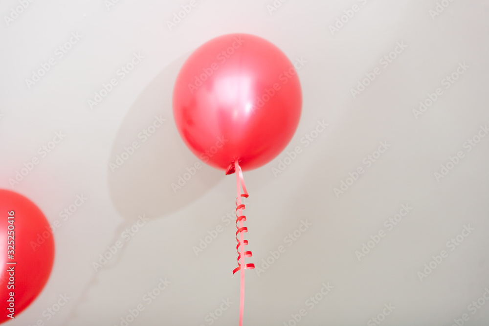 red and pink helium balloons with curly ribbons on gray background during celebration red and pink helium balloons with curly ribbons on gray background during celebration