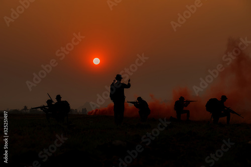 Silhouette pictures of soldiers with guns in the sunset time. War, soldier army, gun and hostage rescue concept.