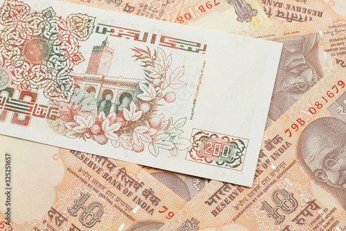 Fototapeta Naklejka Na Ścianę i Meble -  A macro image of a beige two hundred Algerian dinar bank note on a background of Indian ten rupee bank notes