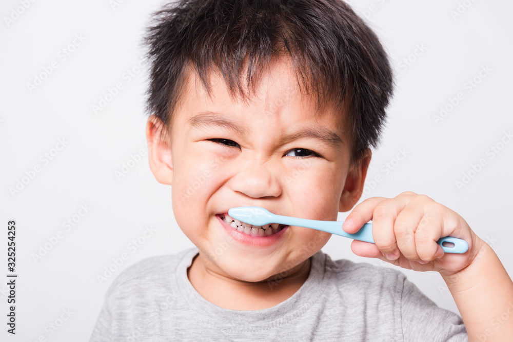 Closeup Asian face, Little children boy hand holds toothbrush he brushing teeth myself Closeup Asian face, Little children boy hand holds toothbrush he brushing teeth myself