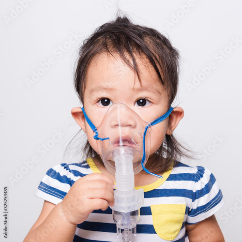 Closeup Asian face, Little baby girl sick her using steam inhaler nebulizer mask inhalation oneself