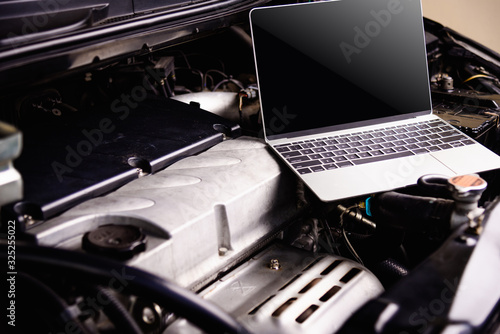 Laptop computer on car mechanic engine for service