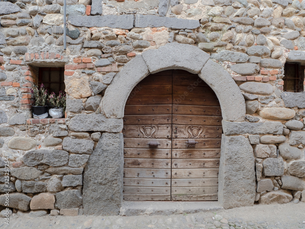 Φωτογραφία Ricetto di Candelo,medieval wooden door with carved heraldic studs and coats of arms framed with stones and bricks