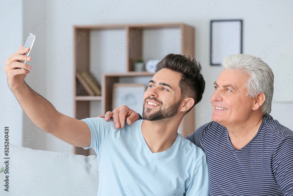 Obraz premium Young man and his father taking selfie at home