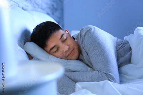 Asian man sleeping in bed a...