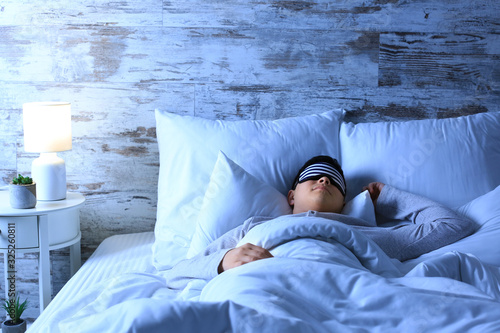 Asian man sleeping in bed a...