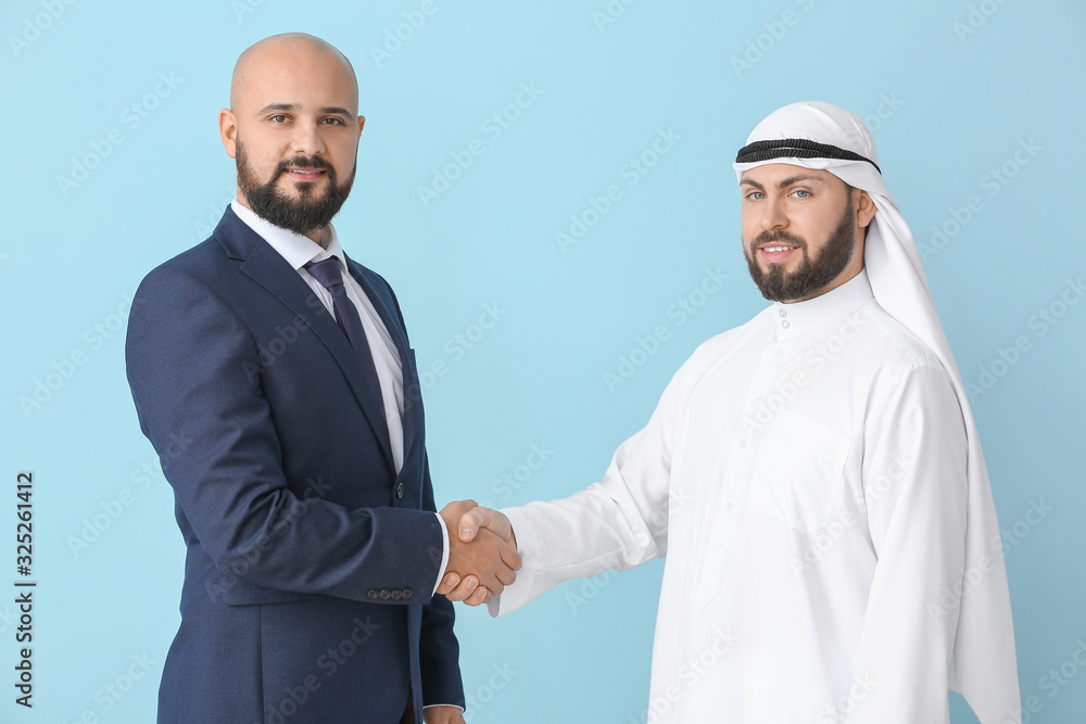 Arab man and his business partner shaking hands on color background Arab man and his business partner shaking hands on color background