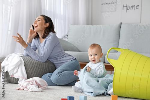 Mischievous baby with careless young mother at home