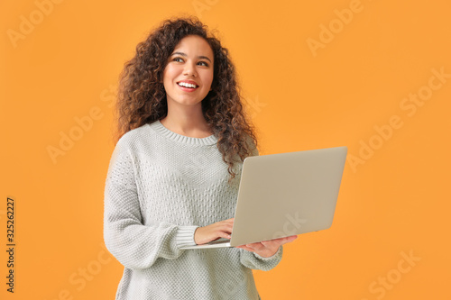 Photography Young African-American woman with laptop on color background