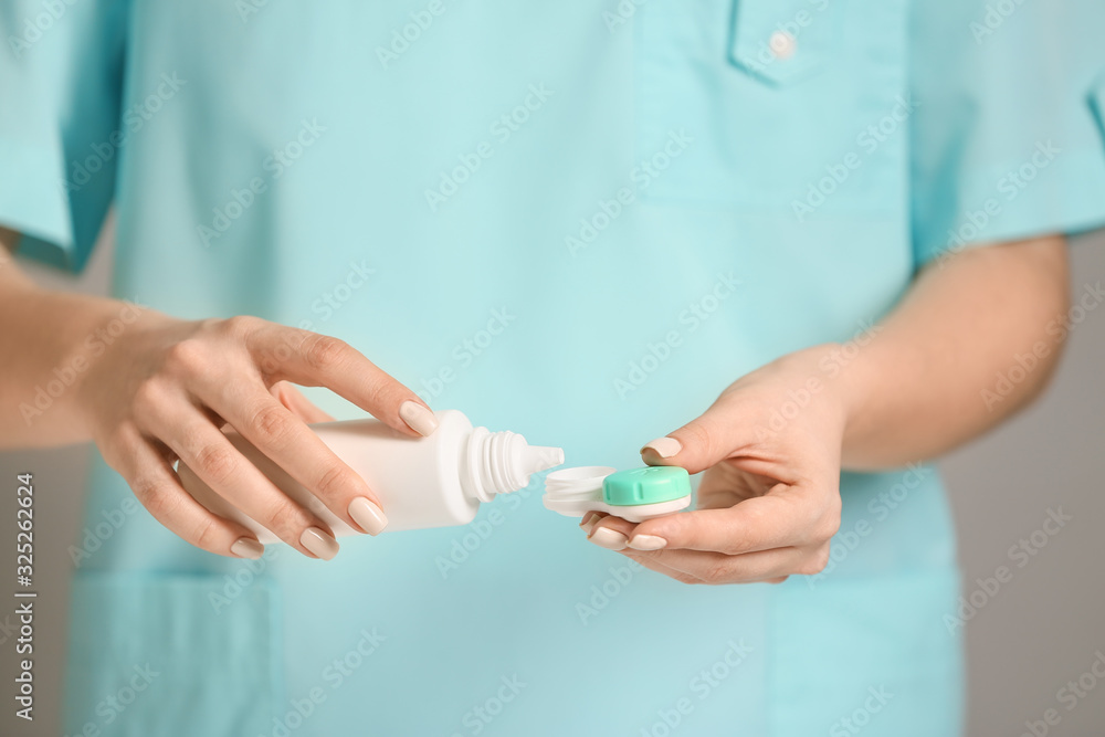 Woman pouring solution in container with contact lenses, closeup Woman pouring solution in container with contact lenses, closeup
