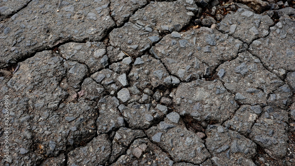 Damaged asphalt road, cracked cracks and scattered stones, with selective focus Damaged asphalt road, cracked cracks and scattered stones, with selective focus