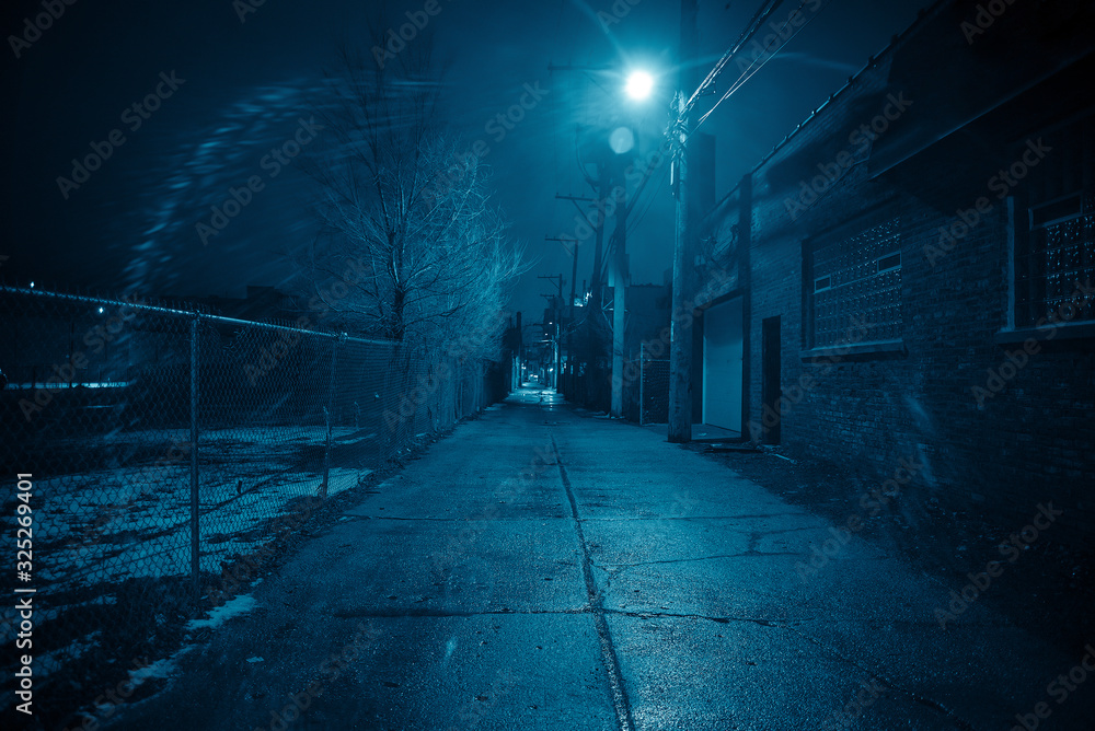 Dark and eerie urban city alley at night in the winter