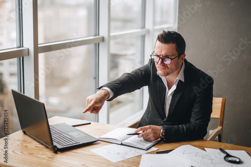 angry manager guy shows finger at subordinate in office at the table