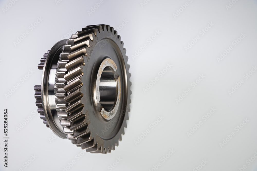 New parts on a gray background. Gears of gear shifting torque transmission. Conceptually mechanical background. Shiny gear box gear teeth New parts on a gray background. Gears of gear shifting torque transmission. Conceptually mechanical background. Shiny gear box gear teeth
