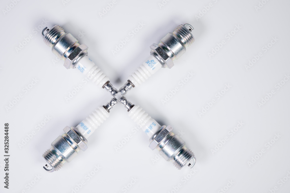 Subject shooting on a gray background. new four spark plugs, spare parts for a gasoline engine. The concept of new auto parts and maintenance Subject shooting on a gray background. new four spark plugs, spare parts for a gasoline engine. The concept of new auto parts and maintenance