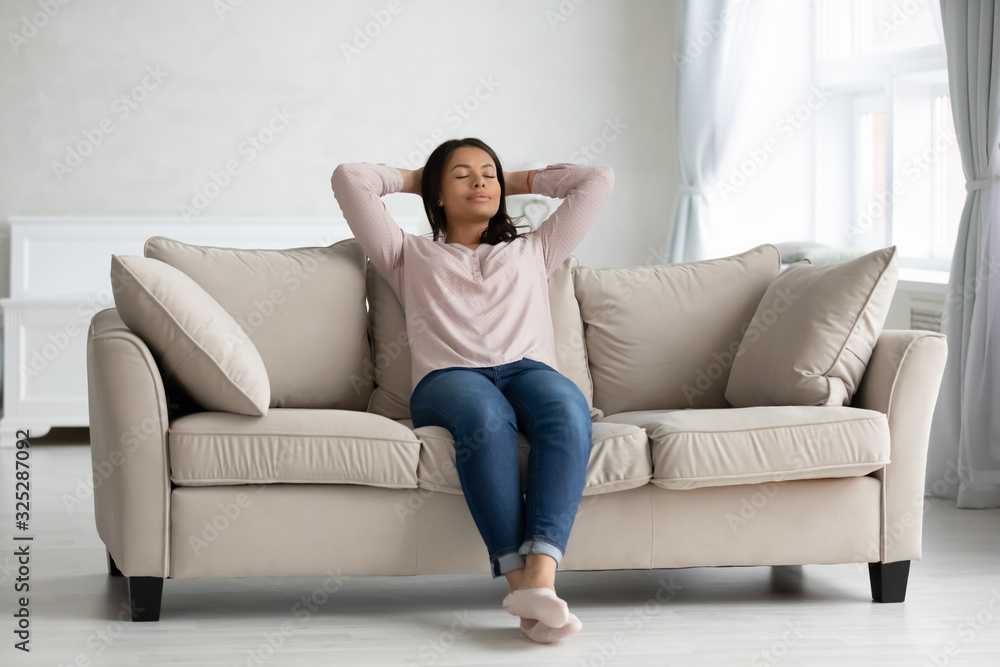 Calm african American woman relax daydream on cozy couch Calm african American woman relax daydream on cozy couch