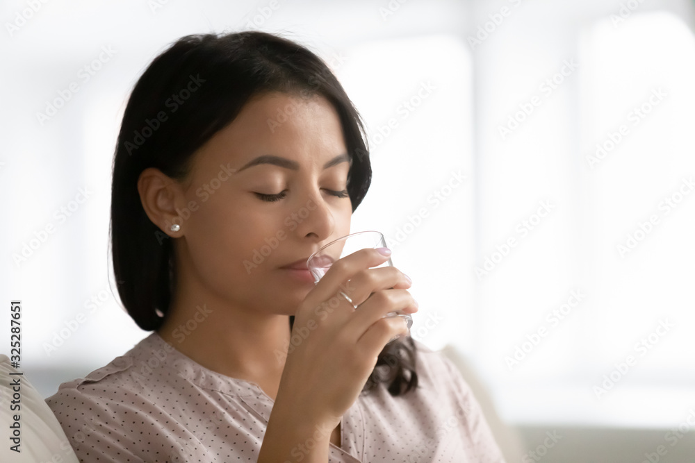 Biracial woman drink pure mineral water from glass Biracial woman drink pure mineral water from glass