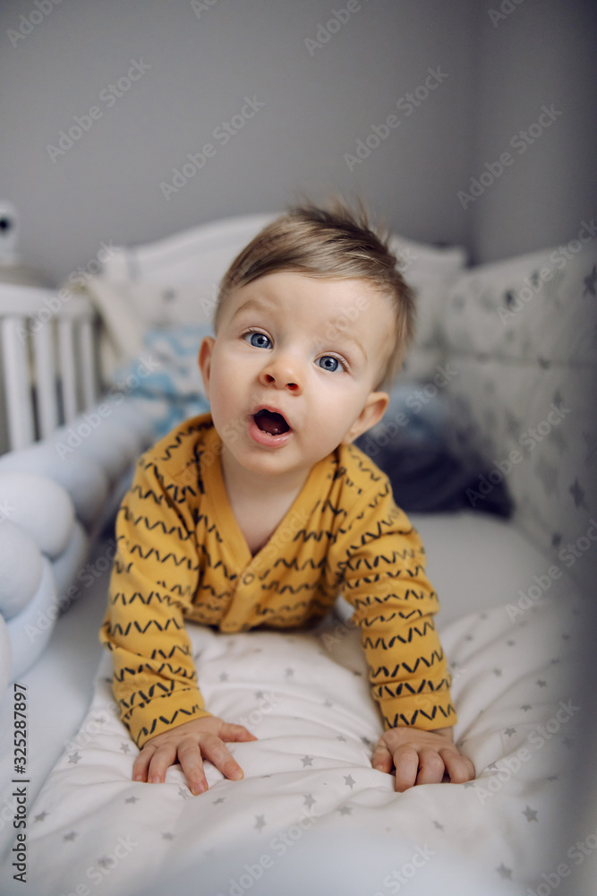 Adorable blond little baby boy with beautiful blue eyes lying on