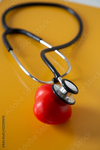 Stethoscope doctors and red heart cardiology placed on a Yellow table in the hospital,  concept: diagnostics disease health prescription for a patient, valentine day symbol Love and care healthcare photo