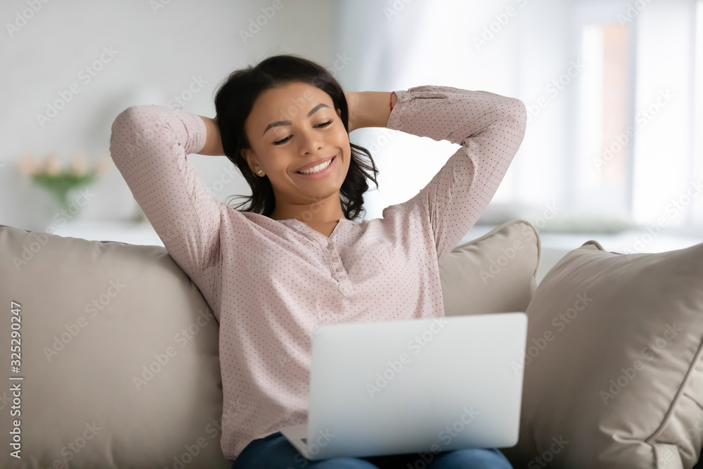 Happy biracial woman relax on couch using laptop Happy biracial woman relax on couch using laptop