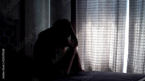 Lonely young woman feeling depressed and stressed sitting head in hands in the dark bedroom, Negative emotion and mental health concept photo