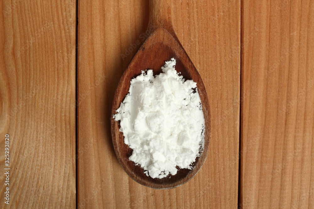 Starch (amylum) on wooden spoon at plank background. Directly Above.
