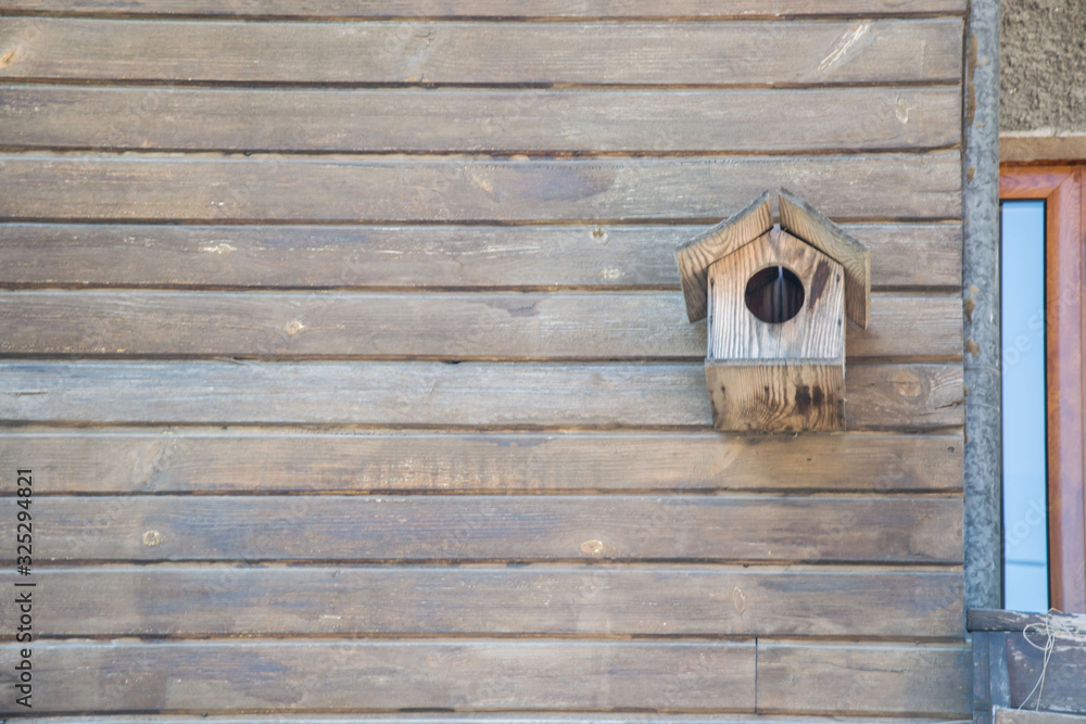Wooden birdhouse on a wooden wall made from planks, background, copy space