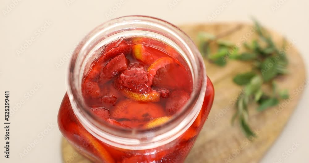 Putting strawberry and lemon marmalade into glass jar Putting strawberry and lemon marmalade into glass jar
